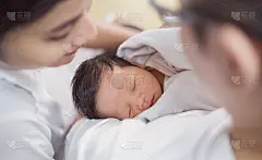 亚洲父母抱着新生儿，近距离拍摄一对亚洲年轻夫妇在医院病床上抱着亲吻他们的新生儿。幸福家庭爱新生儿幼儿