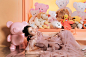 This may contain: a girl in a pink dress laying on the floor with stuffed animals and toys behind her