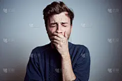 年轻困倦沮丧的男性少年独自在工作室打呵欠。真实的人的情绪，疲倦，疲惫