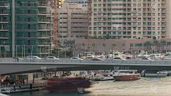 在迪拜滨海区，游客乘坐的游艇和船只停留在购物中心附近，并从桥下经过