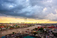 曼谷清晨的日出在泰国的大皇宫上空，是泰国湄南河上的小船，下雨的时候天空是灰色的。暴风雨就要来了。
