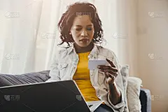 非洲人或黑人手看名片或信用卡，用笔记本电脑在家里搜索或网上购物的概念。