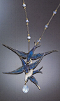 LUCIEN GAILLARD - AN ART NOUVEAU ENAMEL AND MOONSTONE NECKLACE. The pendant necklace designed as triad of diving birds embellished by varied blue enamels accented by a moonstone bead drop, suspending by a fancy link chain of black enamel bar links alterna