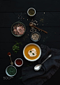 Pumpkin soup with cream, seedsand various spicesl in rustic metal bowl over grunge black background.