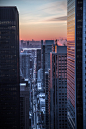 A glimpse of the sunset through with the traffic flowing beneath through the skyscrapers of a city
