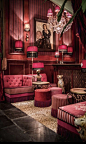 a living room filled with lots of pink furniture and chandelier hanging from the ceiling