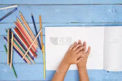 孩子们用铅笔在蓝色桌子上的画册里画画