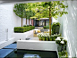 Reflective qualities of white and water brighten narrow back garden with high walls.: