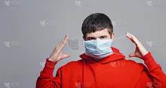 肖像严肃的年轻拉上了口香糖的医疗口罩在灰色的工作室背景上，人准备对抗疫情，检疫措施和保健理念