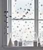 窗户用小纸屋、树和雪花装饰成简洁的冬日仙境风景画。