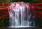 Pier Fabre suspends red strings over waterfall pool : Red strings stretch from the top of a waterfall over the pool below in this installation by Pier Fabre for the Horizons Sancy festival in France.