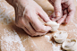 woman folds the raw dumplings on a sheet of parchment