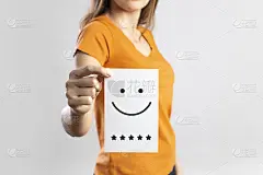 客户体验概念与企业满意度调查。一个年轻女子拿着一张白色卡片，上面写着笑脸