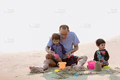一家人在海滩上玩耍。夏天，父母和孩子们在海滩上放松。幸福健康的家庭，爷爷和侄子在沙滩上建造沙堡，面带