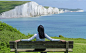 Woman Sitting on Deck Chair by Sea