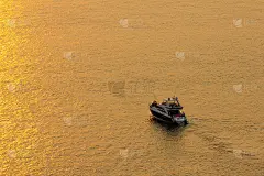 海面上的夕阳把太阳反射成金色。游园游船去看美丽的太阳。