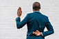 非裔美国外交官站在砖墙附近手指交叉的背影