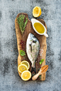 Fresh uncooked dorado or sea bream fish with lemon, herbs, oil and spices on rustic wooden board ove by Anna Ivanova on 500px