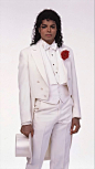 This may contain: a male in a white suit and red flower