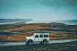 A white off-road vehicle on a dirt road with a misty shoreline at the back