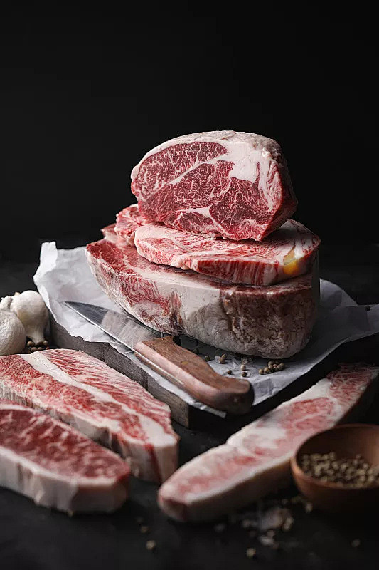 特写肉在砧板上对黑色背景照片素材