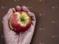 手放在棕色背景上的茜苹果