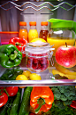 Fresh raspberries in a glass jar on a shelf open refrigerator