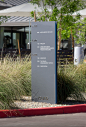 An internally illuminated Corten steel monument with routed faces marks the entry of the campus.