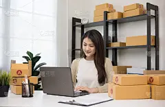 年轻的亚洲女企业家检查产品的股票与笔记本电脑注意。女商人在家中从事中小企业在线工作。检查包裹上的地址