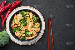 黑碗湖南鸡，暗石板背景。湘鸡是一种中式或印度支那风味的外卖菜，搭配西兰花、西葫芦、香菇和湘菜酱。本空
