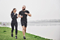 Couple jogging and running outdoors in park near the water. young bearded man and woman exercising together in morning