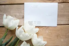 白色郁金香花束和木制背景上的白色空白模型。复活节或母亲节贺卡