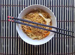 白花蔬菜面放在白色的瓷碗里，两根筷子放在竹制的餐垫上。从以上观点。