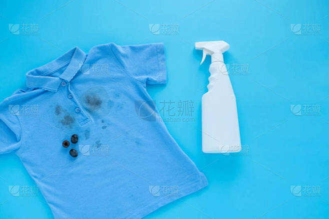 衣服上的黑橄榄污渍和去污剂。污渍清洁剂，顶视图。被蓝色的背景隔离了高质量的照片