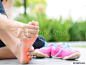 Soft focus woman massaging her painful foot while exercising.   Running sport injury concept.