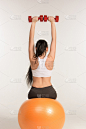 年轻的女运动员做健身运动与哑铃在普拉提球