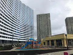 城市景观，蓝白相间的高层公寓楼。旁边有一所形状奇特的房子，像波浪一样。在城市中心有高楼和娱乐的城市现