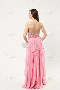 全身照片的时装模特女人穿着优雅的晚礼服粉红色礼服摆姿势孤立在白墙背景的工作室肖像。黑发长发的女孩。模
