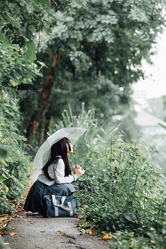 亚洲女学生的肖像与伞在自然步道上下雨