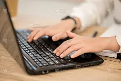穿着白衬衫坐在电脑前打字的亚洲职业女性。