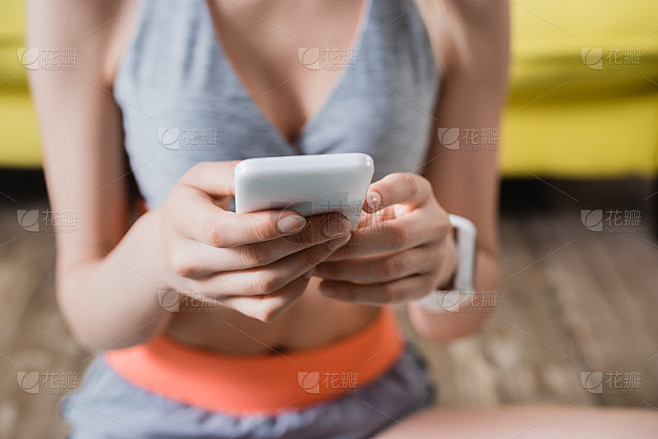 抱着手机的女运动员的裁剪视图