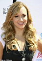 Andrea Bowen - long curly hair.  The hair is brushed smooth and ¾ of the hair is curled in larger sections and tousled. A section of the hair in front is styled slightly over the forehead. The hair is parted off-center but there are many ways to part the 