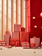 Gifts with red boxes and gold foil on a shelf, in the style of scattered composition, luminous hues, monochromatic abstractions, polka dot madness, light red, tabletop photography, stripes and shapes