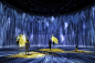 油罐中的水粒子世界, 消除作品的边界 / Universe of Water Particles in the Tank, Transcending Boundaries | teamLab : 本作品超越了作品间的界线，与其他的作品相互影响。在油罐的空间里，从天而降，形成了巨大的瀑布。水用无数水粒子的连续体来表现，计算粒子之间相互影响，接着根据这些水粒子的移动在空间中描绘出线。而这些「线的集合」就形成了teamLab所构想的超主观空间中的平面瀑布。当人站立在作品上时，人会成为能够阻挡水流的岩石，观赏者自