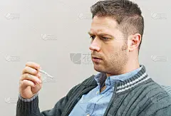 伤心英俊的男人看着温度计。