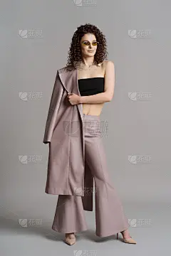 女人在皮革时尚的衣服和绿色太阳镜在工作室灰色的背景
