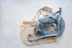 两个针织网眼环保购物袋在一个浅色背景，自然线购物者，生态友好的生活方式，零浪费的概念