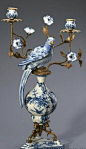 a blue and white vase with two birds sitting on it's base next to three candlesticks