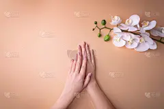 时尚，女性手用美甲，指甲护理，白色兰花花，健康肌肤和天然化妆品的概念。俯视图与粉状背景形成对比。
