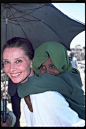 Ethiopia, 1988 - UNICEF Goodwill Ambassador Audrey Hepburn smiles as she carries a child on her back, under the shade of an umbrella, in the town of Mehal Meda in the northern part of the province of Shoa. Ms. Hepburn was visiting a food distribution cent